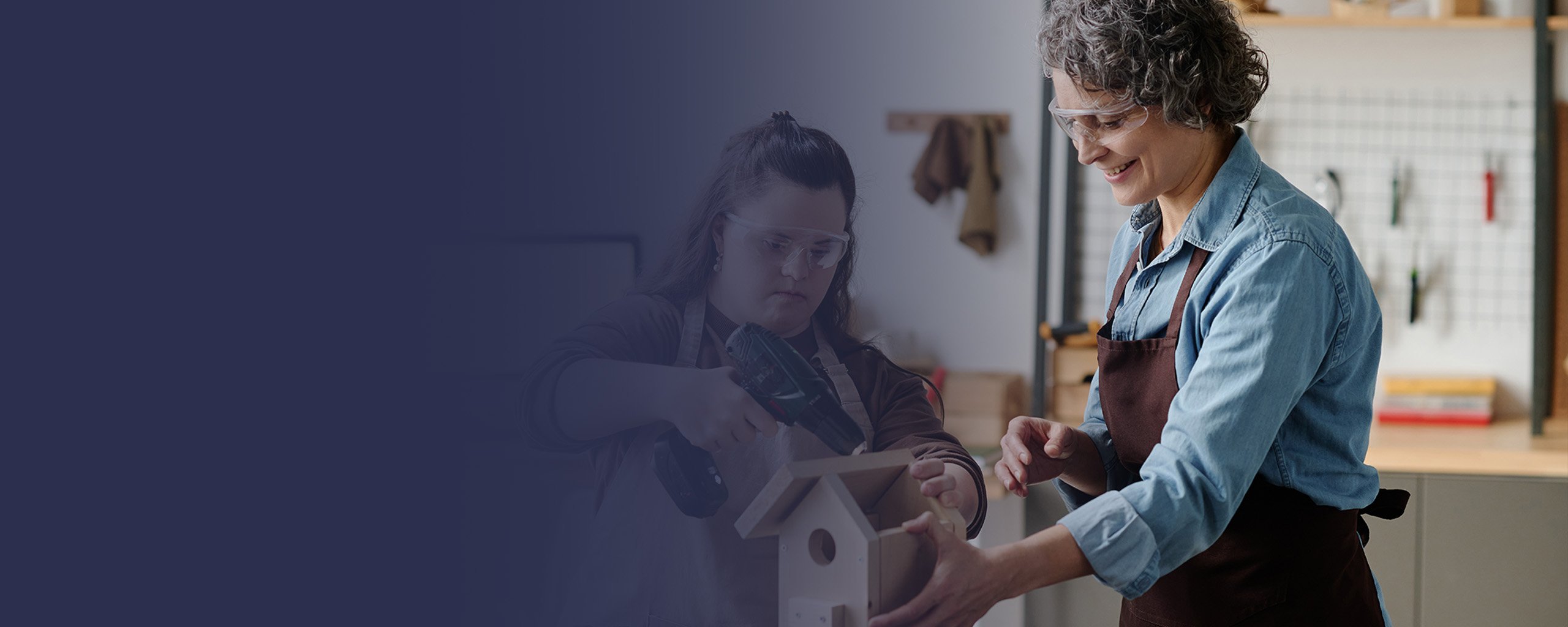 Eine junge geistig behinderte Frau mit einer Betreuerin beim Arbeiten in einer Behindertenwerkstatt